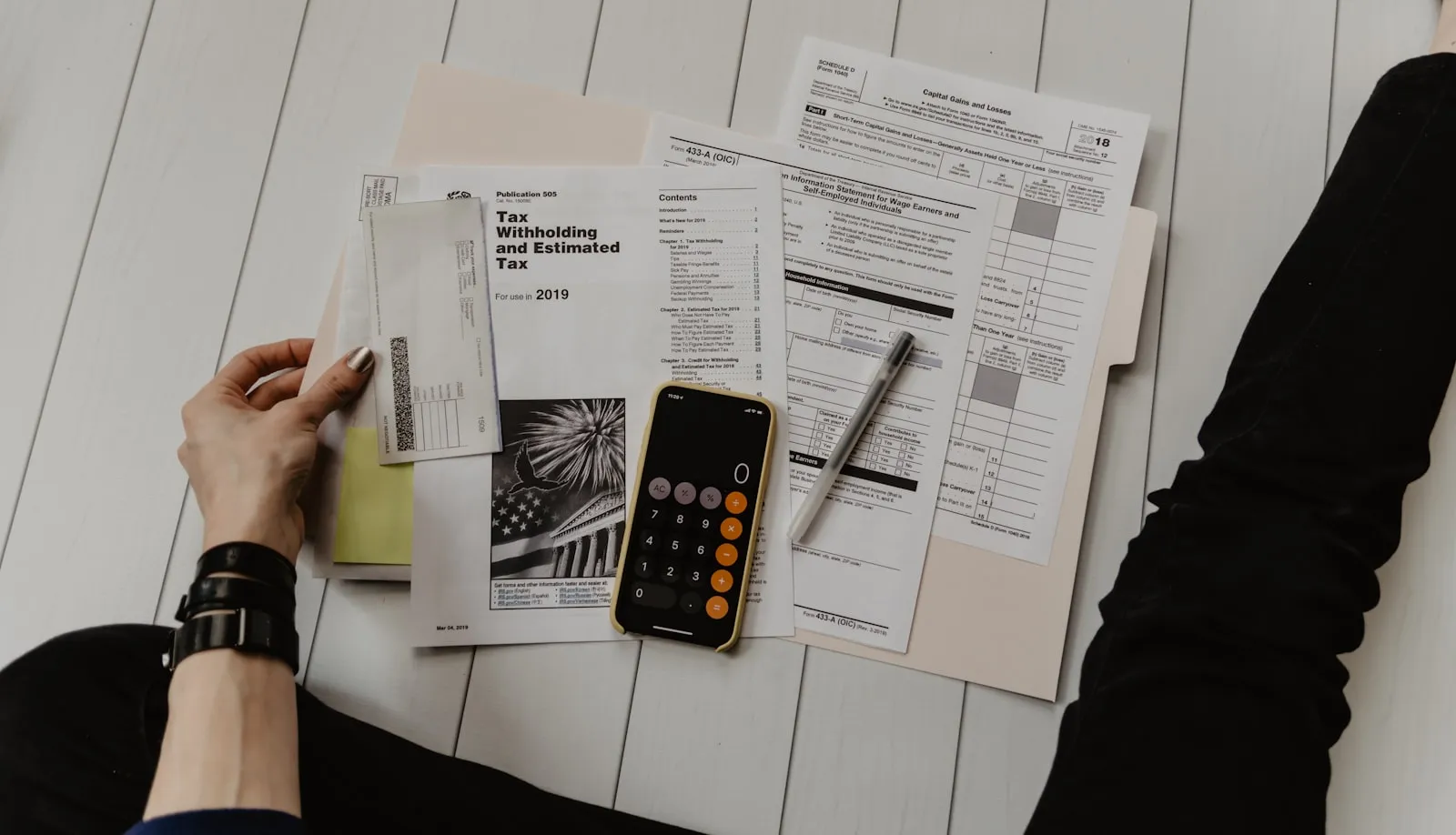 Pen and calculator on top of tax forms and a deduction worksheet
