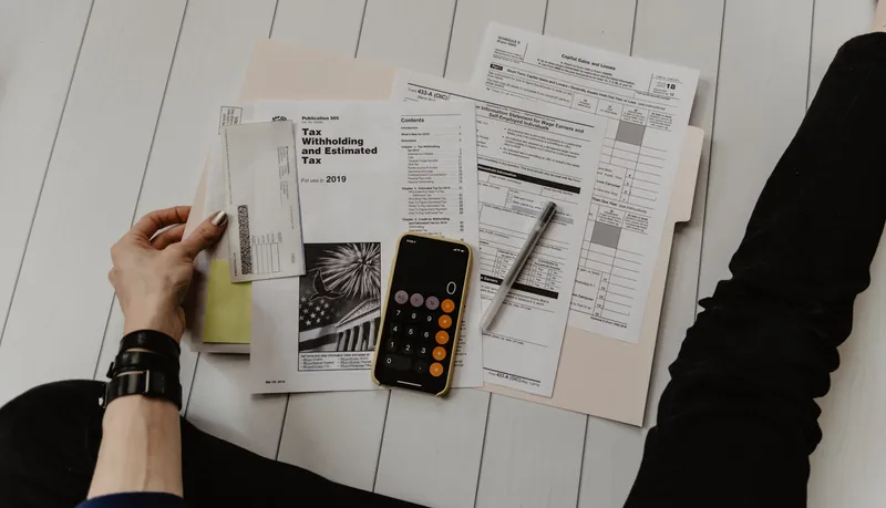 Pen and calculator on top of tax forms and a deduction worksheet